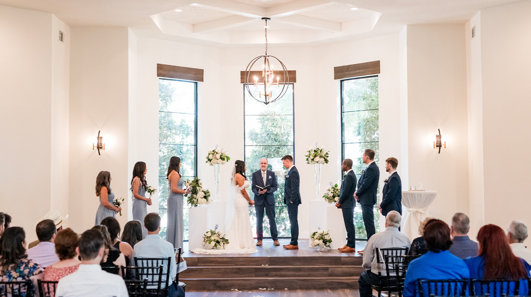Exterior of Hayes Hollow wedding venue with white brick arches, stone accents, black double doors, and landscaped entry