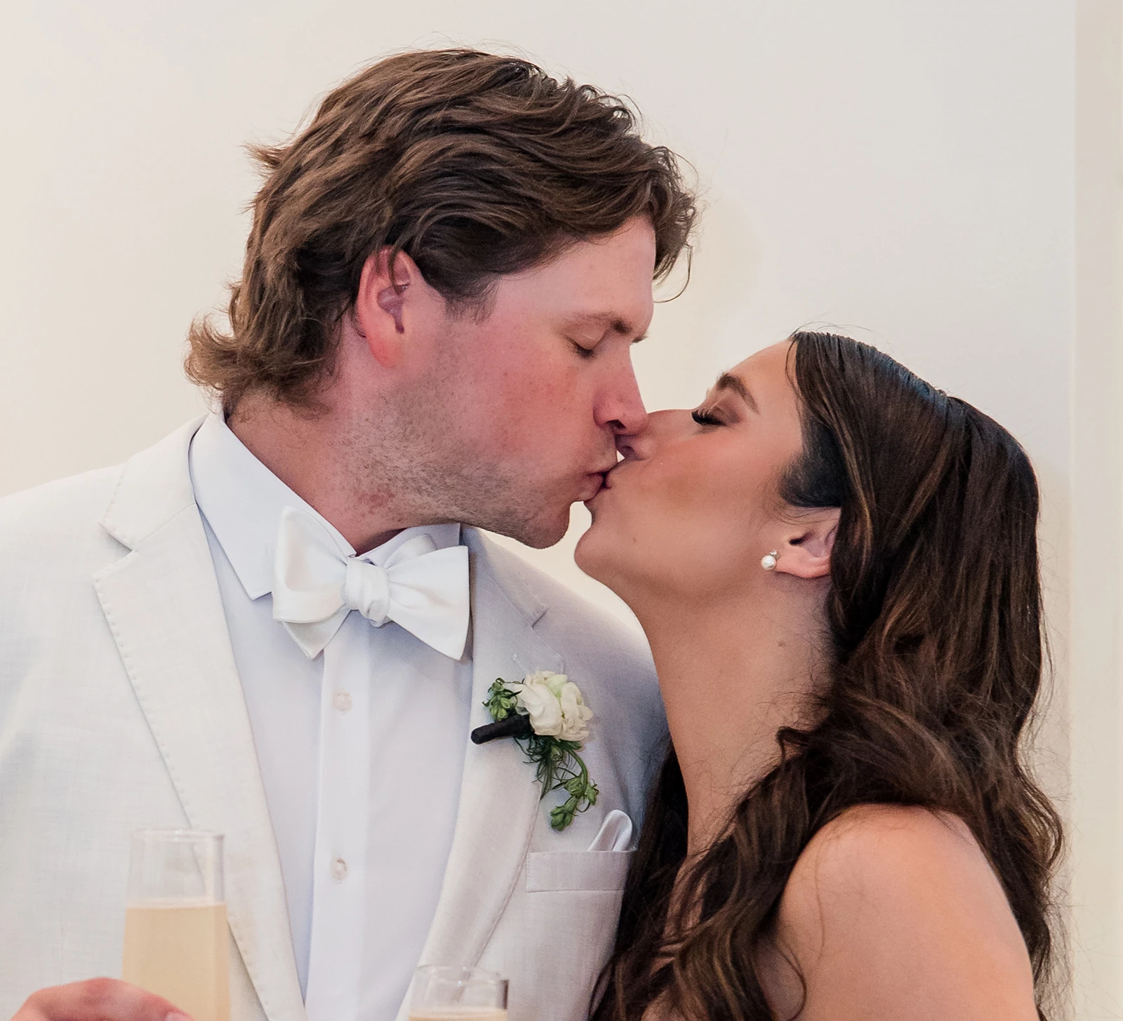 Bride and groom sharing a kiss while holding champagne glasses during their wedding celebration
