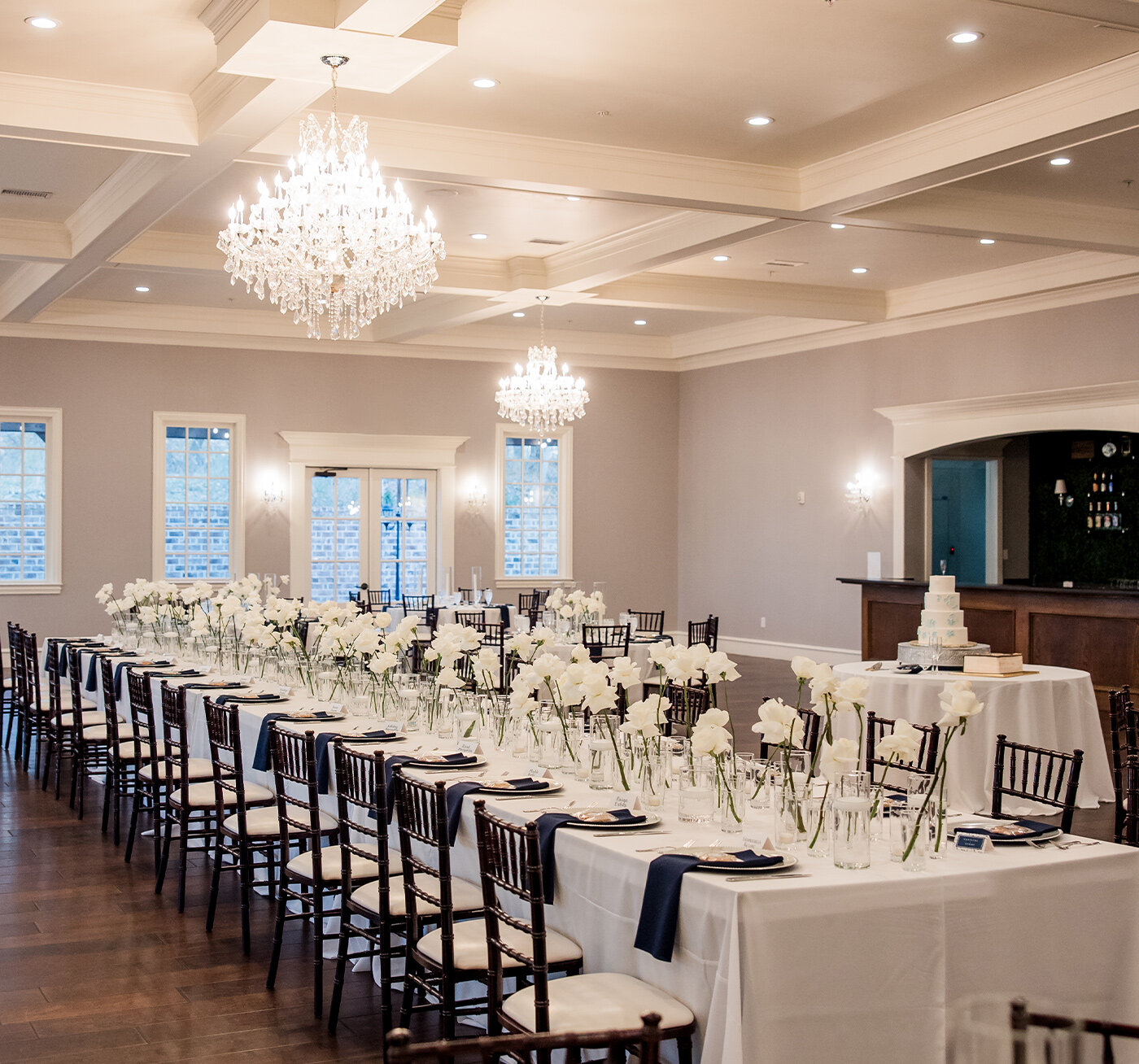 Curved wooden staircase decorated with lush white and peach floral arrangements in an elegant indoor wedding venue.