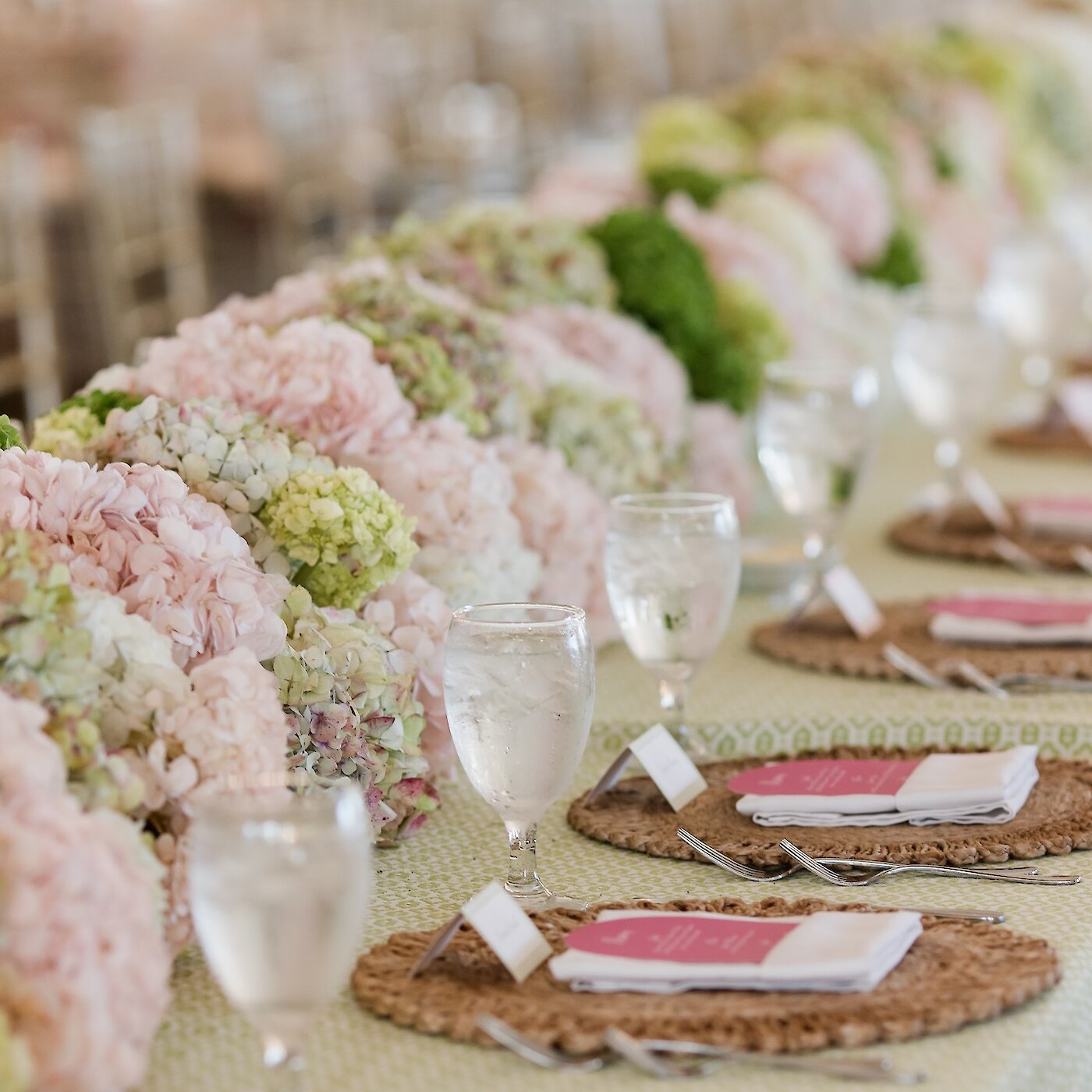 Wedding reception table arrangement with hydrangea flowers, place cards and water for guests.