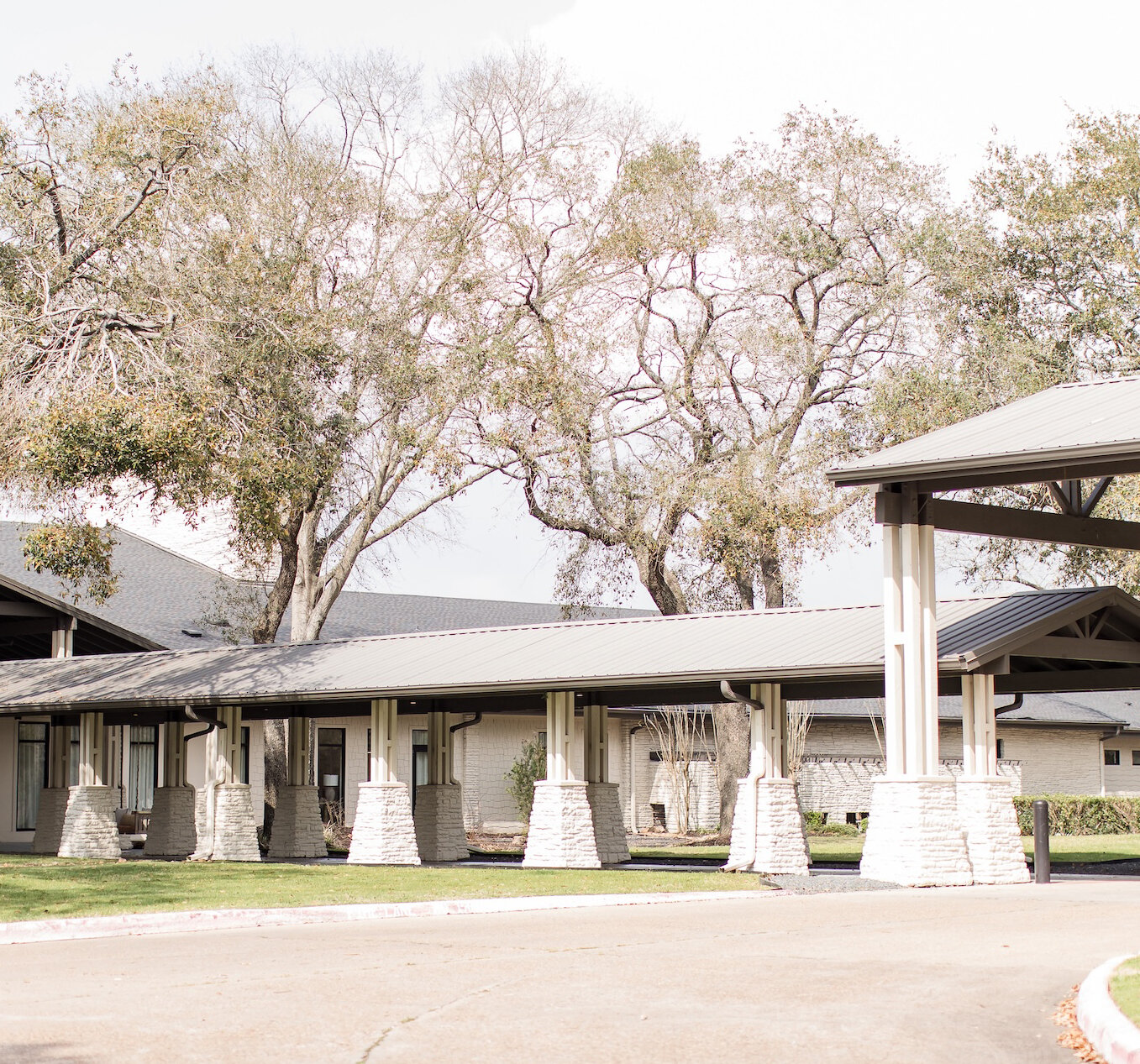 Striking modern A-frame glass wedding chapel with black trim and a white brick facade on a sunny day.