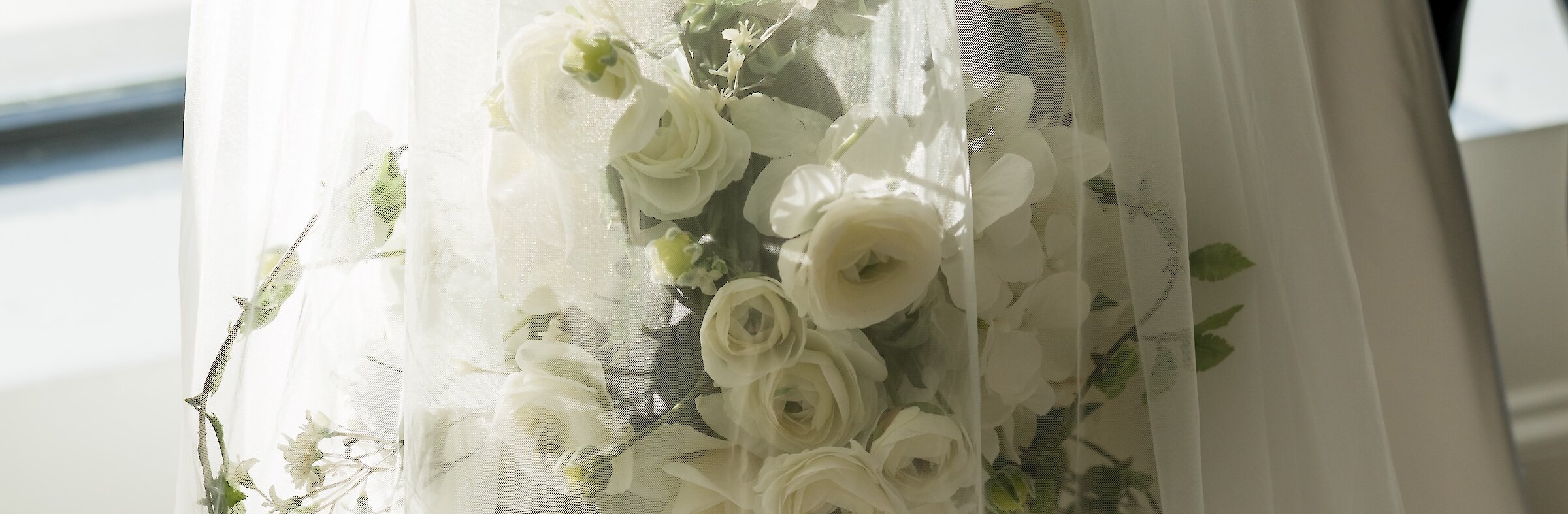 White bridal bouquet wrapped in transparent white veil