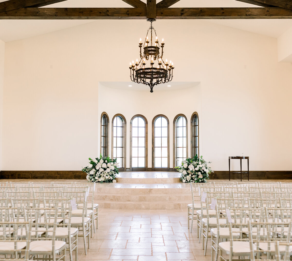 Bride and groom holding hands in front of brick chapel with ornate black arched front door