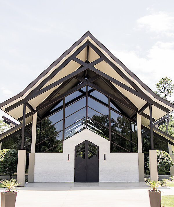 Modern wedding venue exterior with dramatic rooflines and glass entrance.