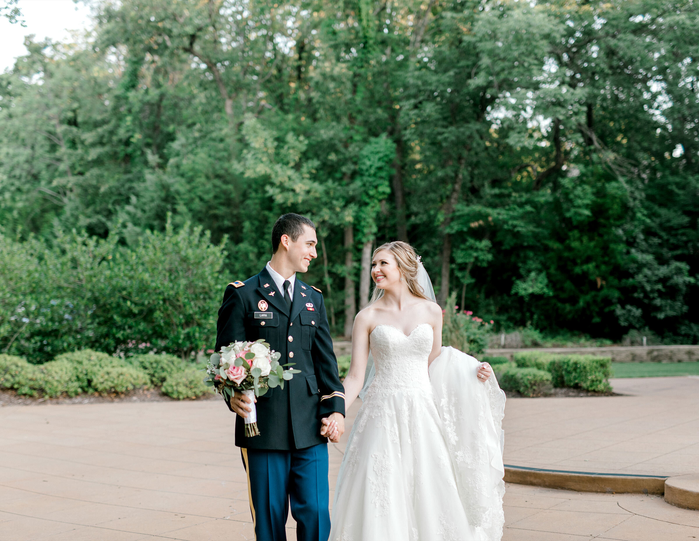 Groom cuddling bride who has a long white train draped down arm