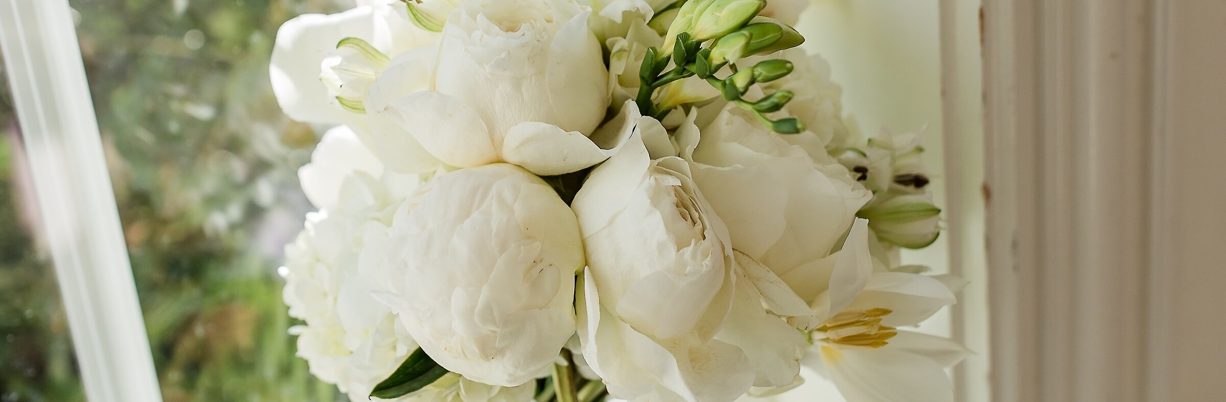 White flowered wedding bouquet standing upright in windowsill