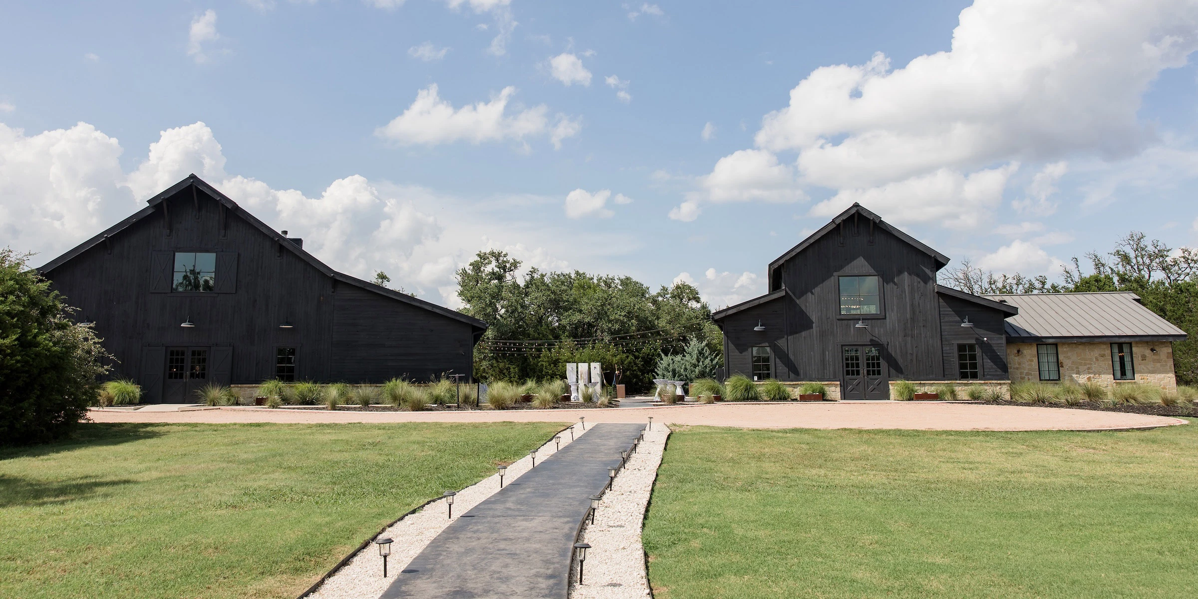 Grass-lined walkway leading to the modern black Morgan Creek wedding Venue