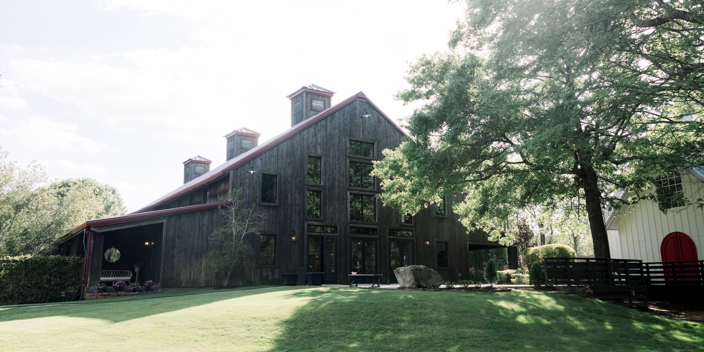 Lush lawn leading to the dark wooden reception hall at The Carriage House wedding venue