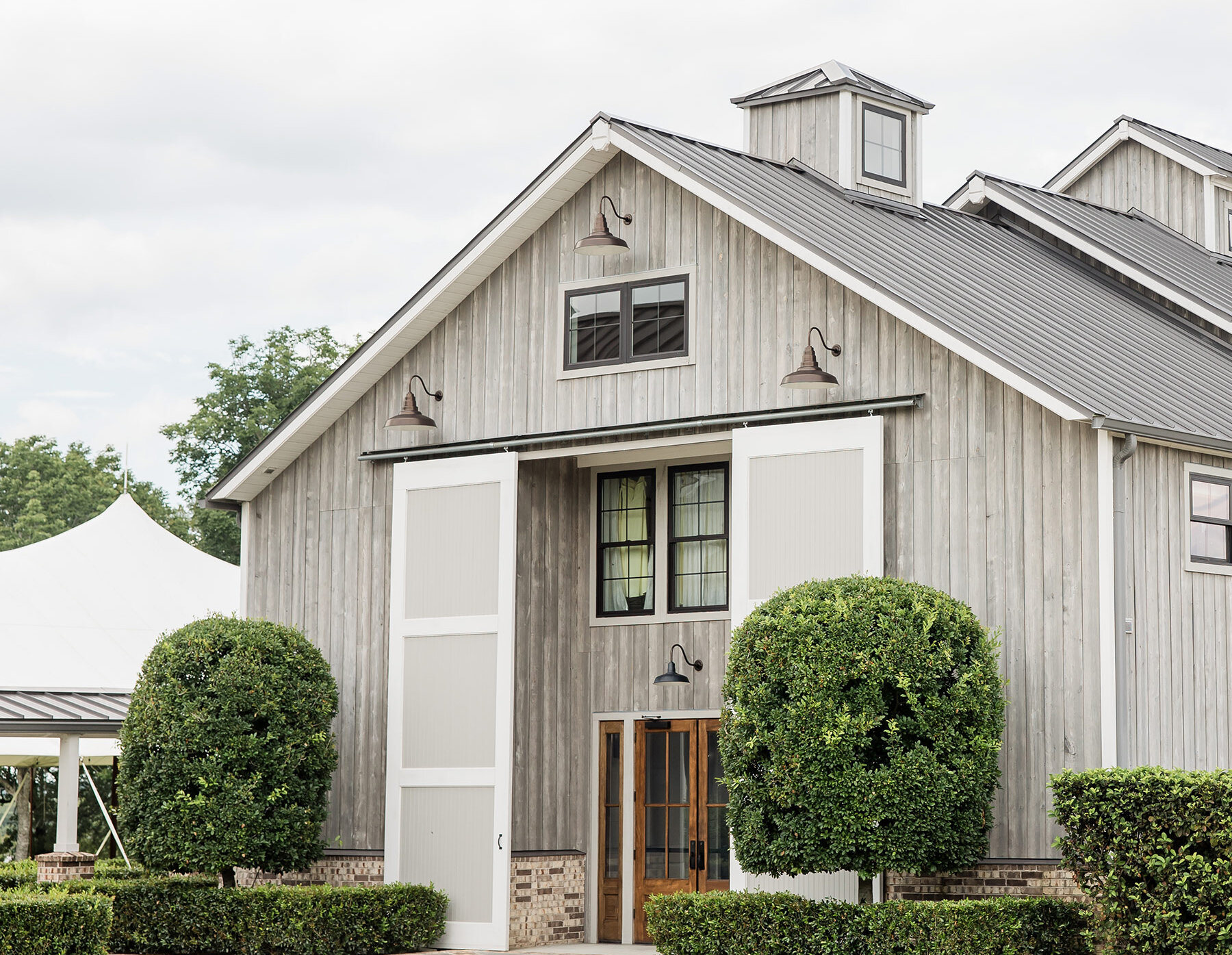 Magnificent luxury wedding venue exterior featuring a French Baroque or neoclassical style with a large dome, dormer windows, and a prominent arched stone entryway. The light-colored stone facade is set against a green lawn and blue sky.