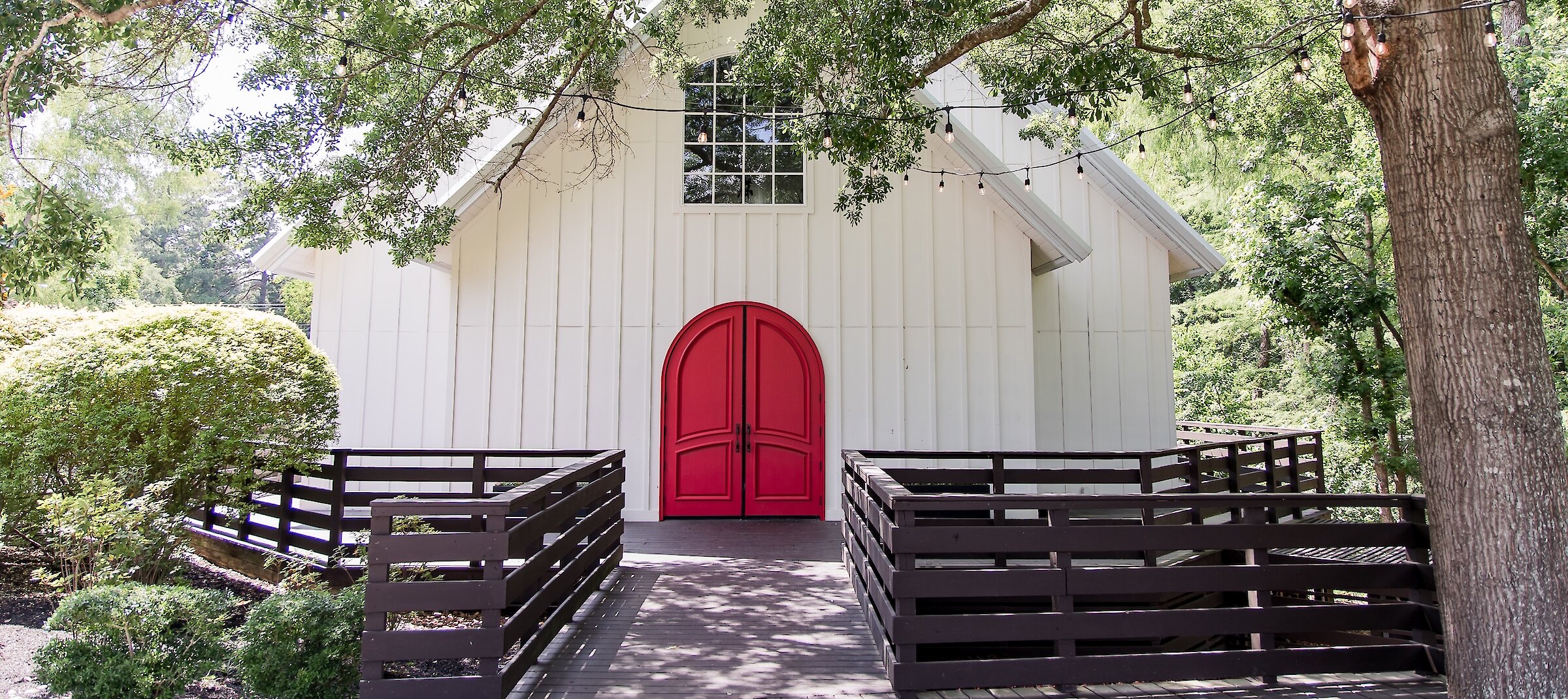 The Carriage House white chapel with red door framed by trees