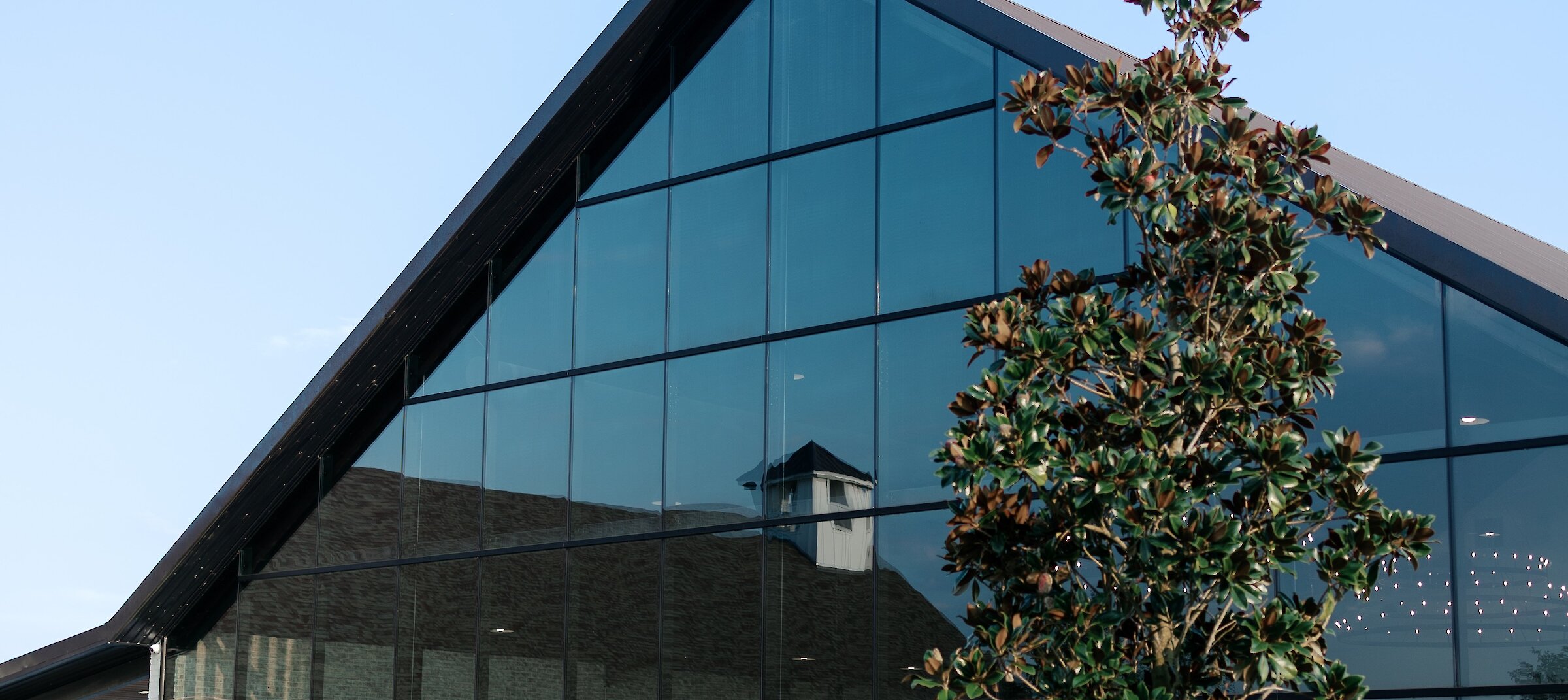 The striking modern exterior of a wedding venue featuring sharp lines, with a full glass wall..
