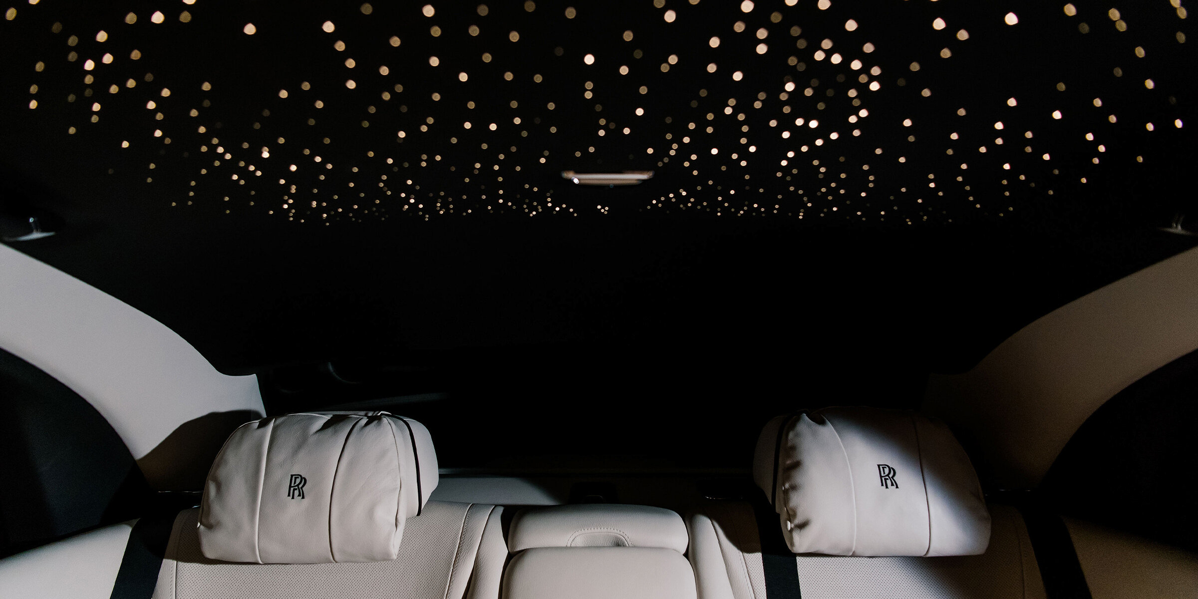 Intimate black and white farewell photo of the newlyweds kissing inside the back seat of a white luxury car, surrounded by floating bubbles from the exit send-off. The bride wears a sequined slip gown.