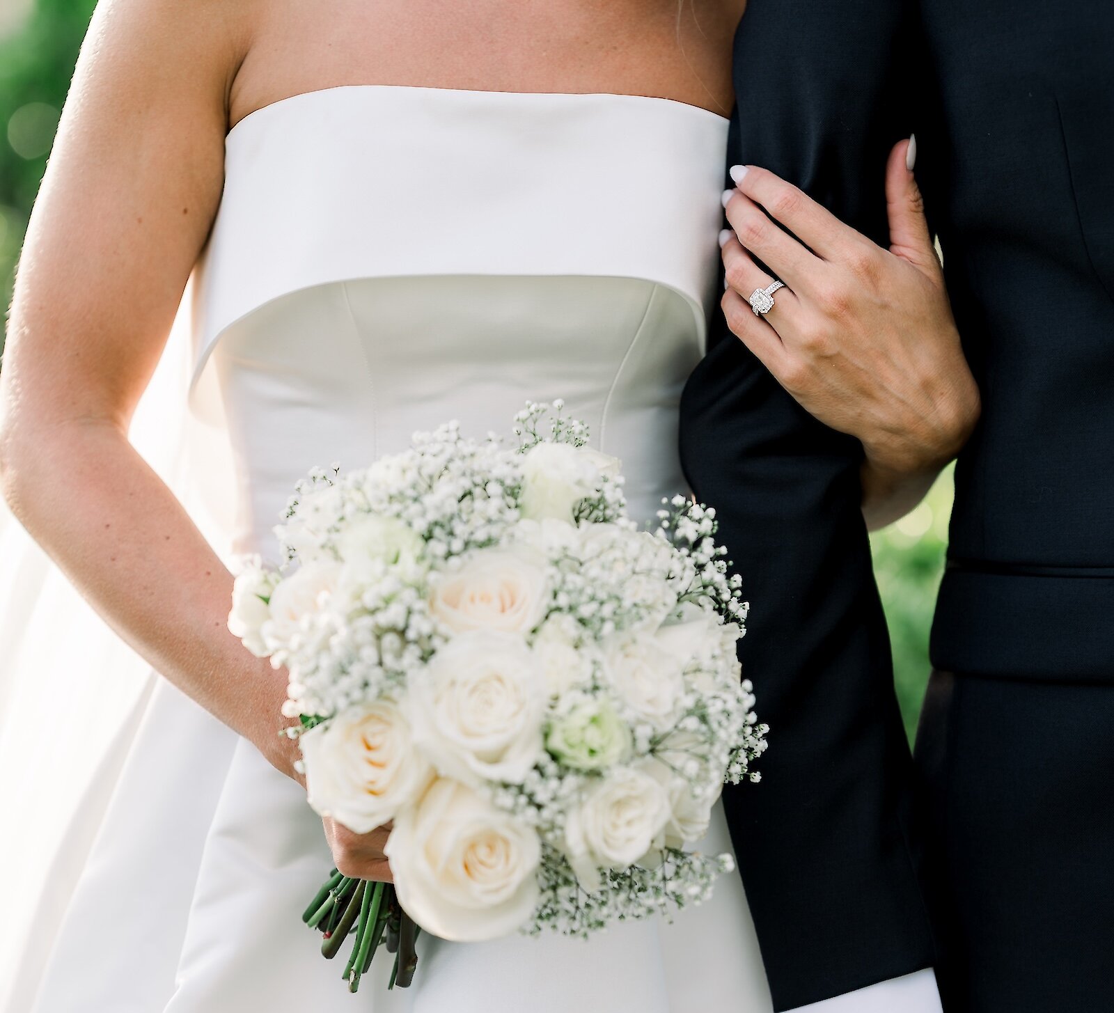 Torso view of bride holding groom's and bouquet in the other hand
