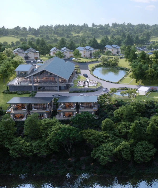 Modern lodge-style building with stone and wood exterior, large gabled rooflines, and a covered drop-off area, surrounded by landscaped greenery at dusk.