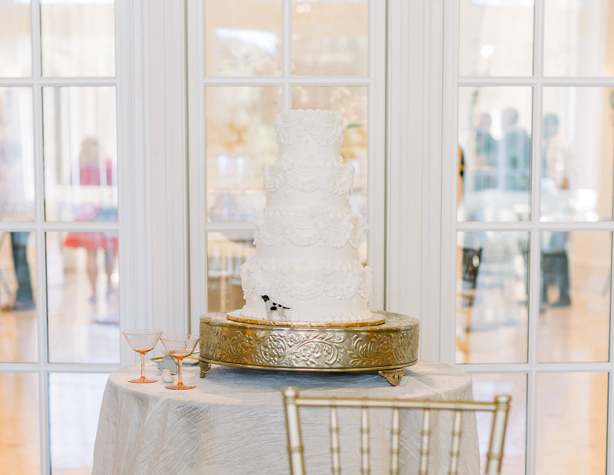 Bride and groom share a kiss while cutting their tiered wedding cake during the reception.