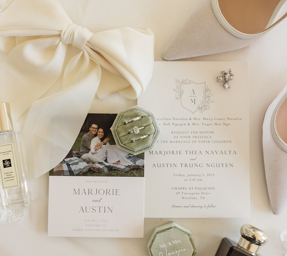 A classic wedding invitation flatlay featuring the invitation, RSVP and details cards with QR codes, pearl necklace, earrings, and wedding rings.
