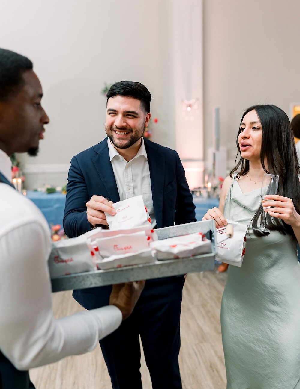 Wedding guests happily receive Chick-fil-A sandwiches from a server as a late-night snack during the reception.