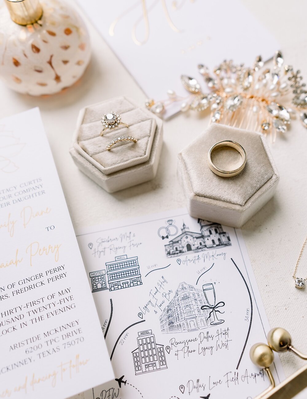 A wedding flat lay featuring the engagement ring and wedding band in velvet ring boxes, an illustrated guest map, and the elegant invitation suite.