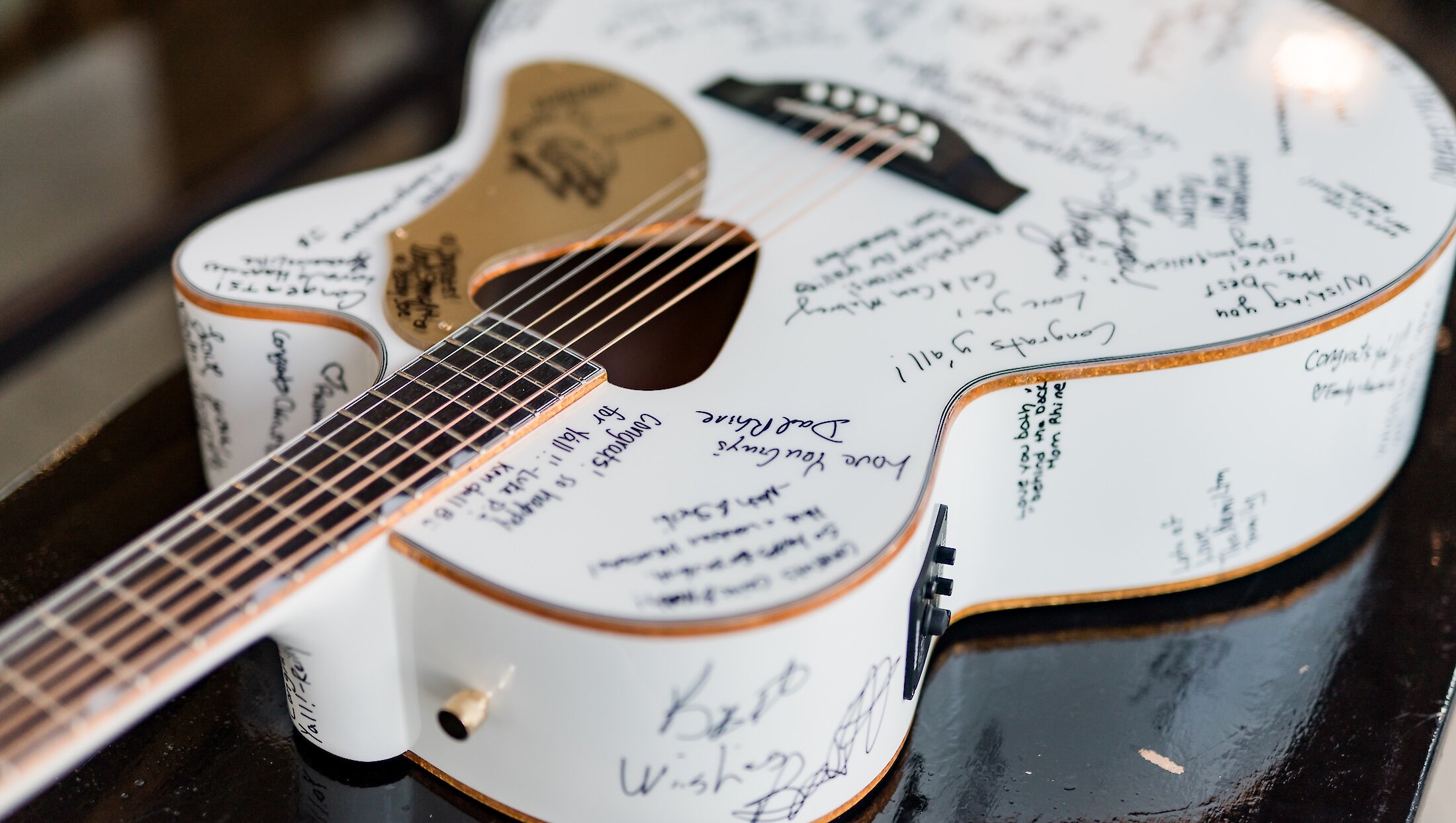 A unique wedding guest book: a white acoustic guitar covered in handwritten signatures and loving messages from the wedding guests.