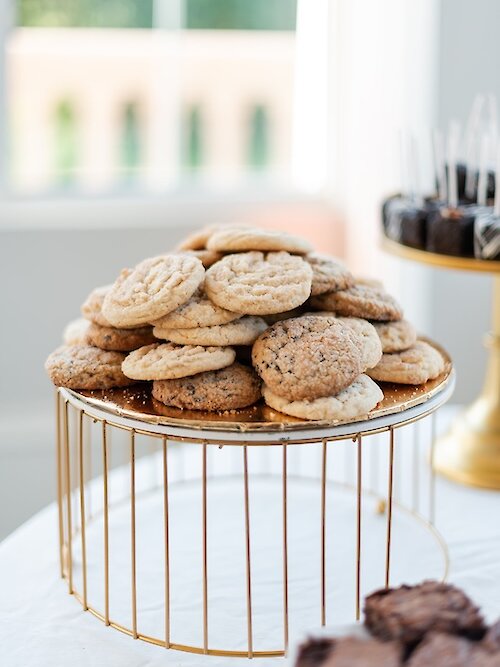 Pile of assorted cookies displayed on a gold wire dessert stand at a wedding reception.