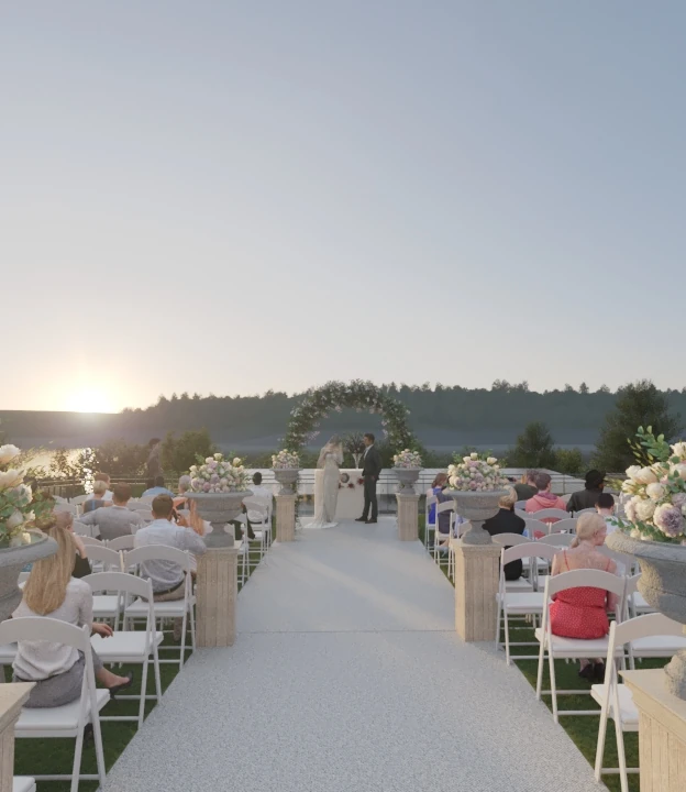 A rendered view of an outdoor sunset wedding ceremony overlooking a lake, with a white aisle, white folding chairs, and floral arrangements in stone urns.