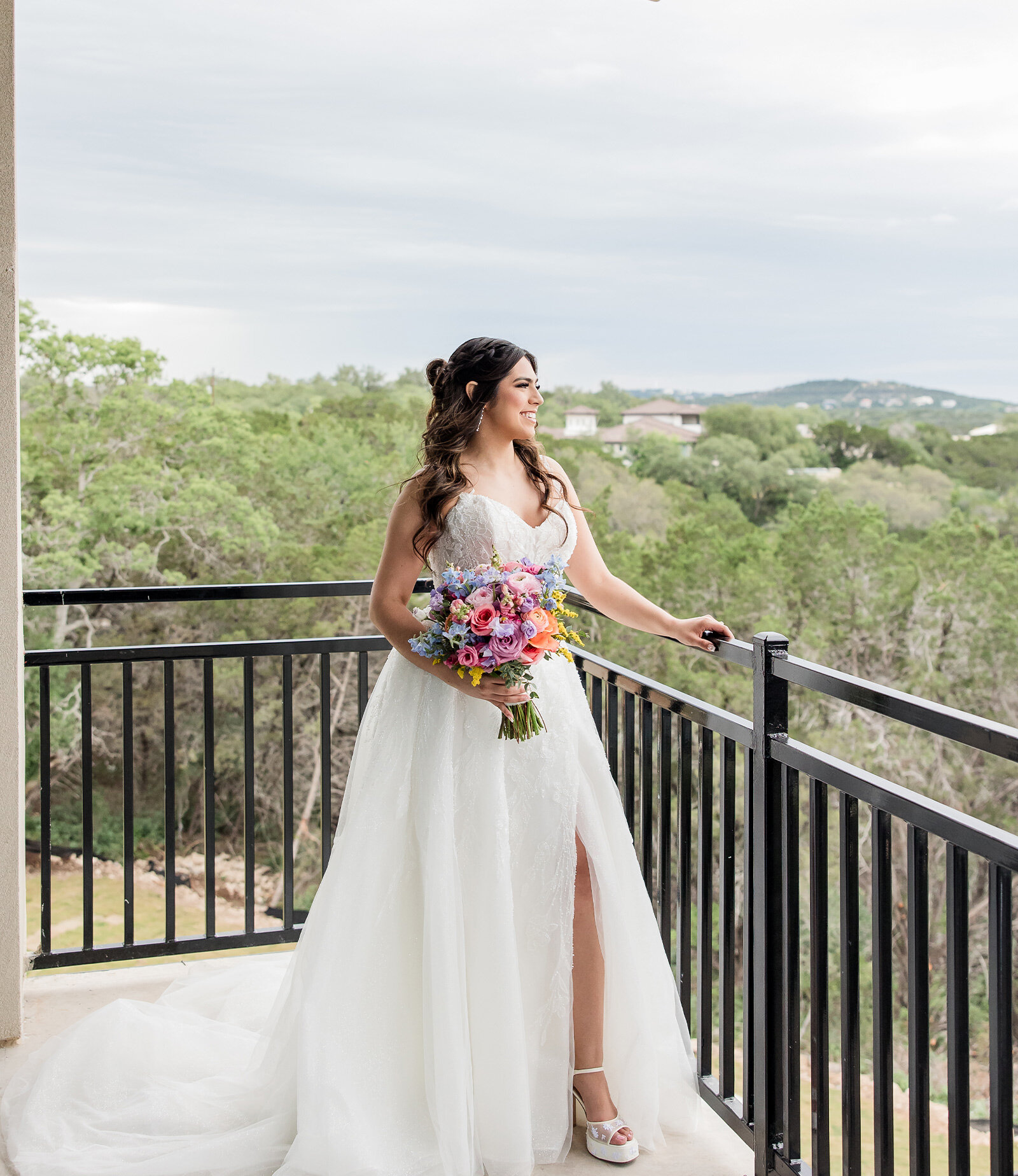 Bride holding bouquet on a balcony looking at the lake