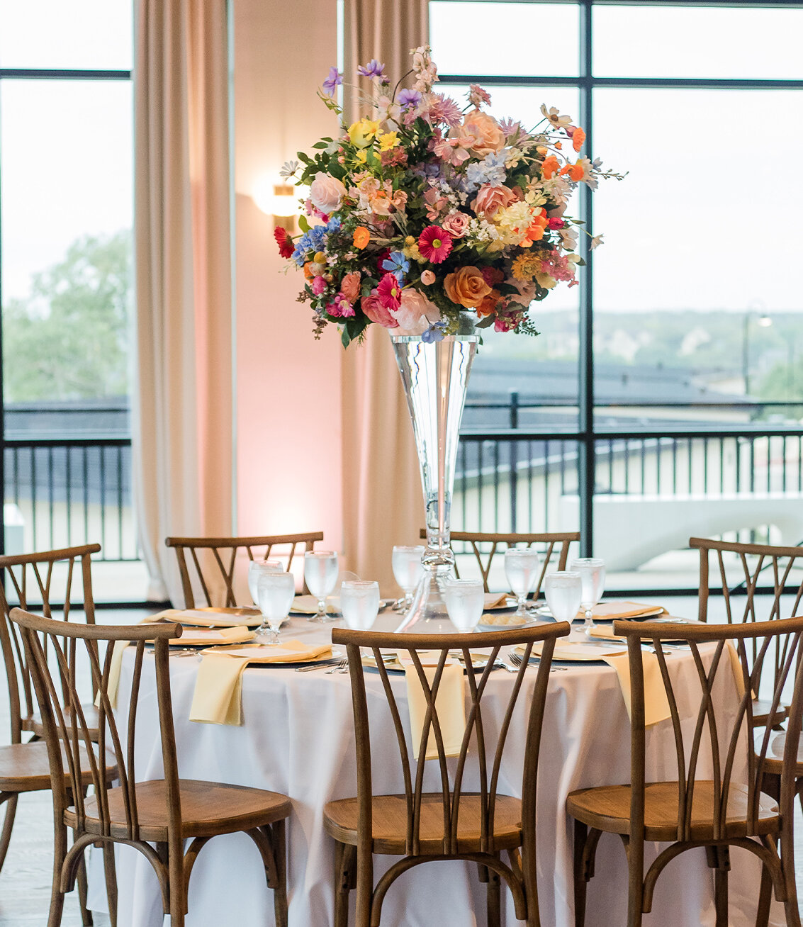 Colorful floral decor inside of reception ballroom with large windows in the background