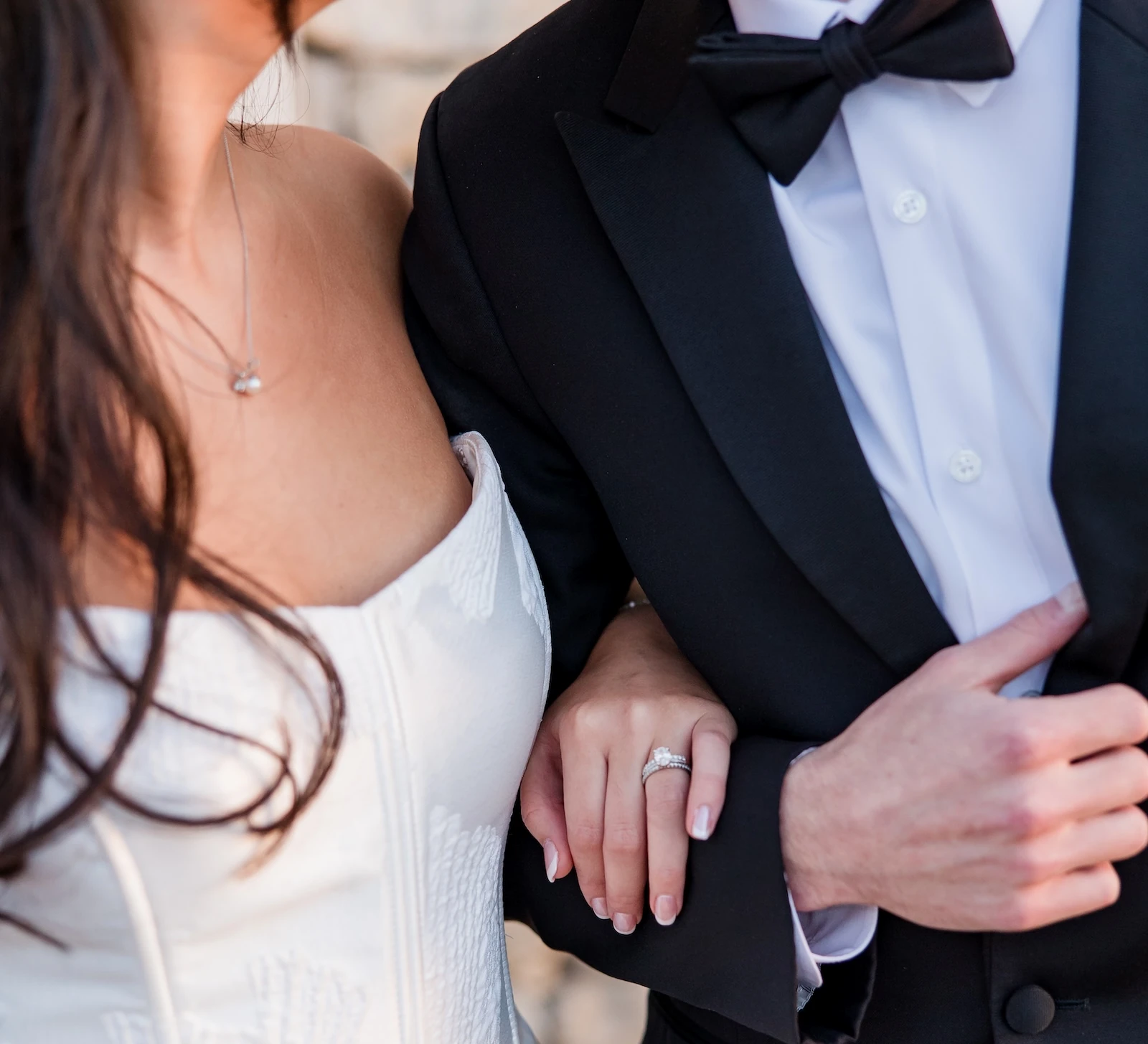 A close-up of a bride and groom embracing, highlighting the large diamond engagement ring on the bride's finger.
