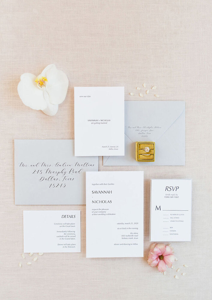 Modern wedding detail photo featuring five light blue table number cards (numbers 1, 2, 3, 11, and 12) with metallic copper/gold numbers, arranged on a gray marbled background with matching light blue knotted fabric.