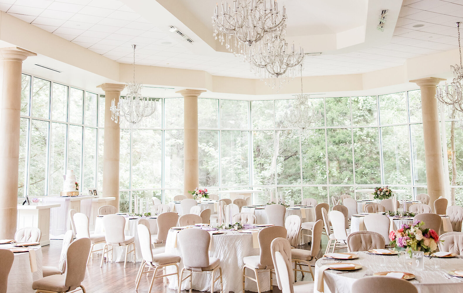 A black and white photo of guests raising wine glasses for a toast over a dinner table with tall candle centerpieces.
