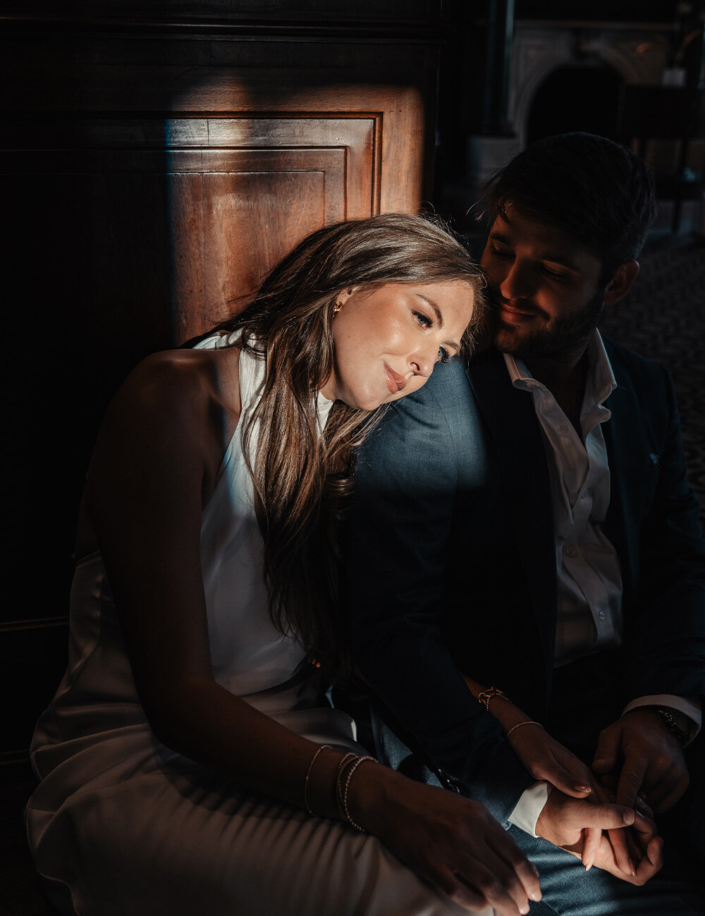 couple holding hands and bride leaning on groom