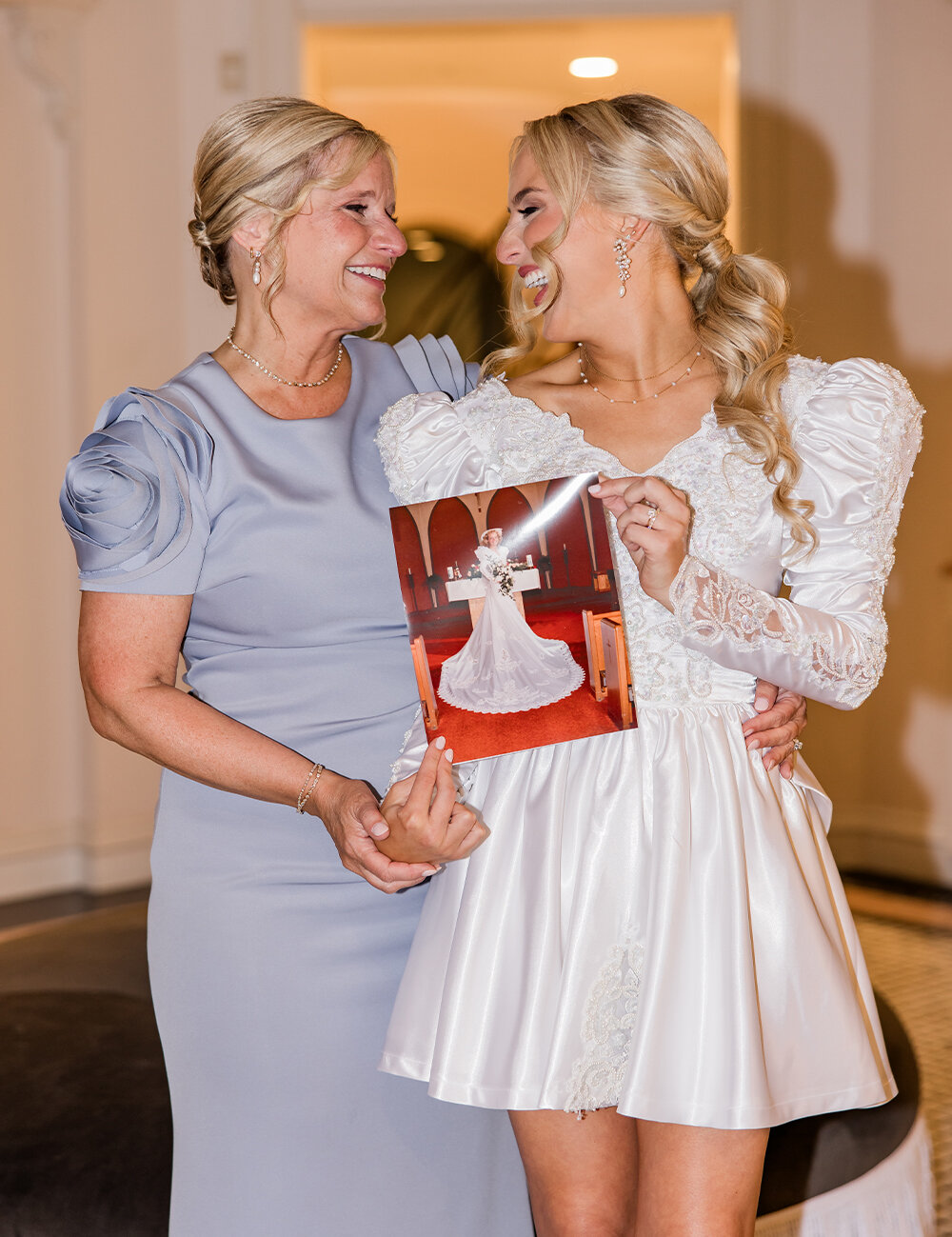 mother smiling at bride holding old photo