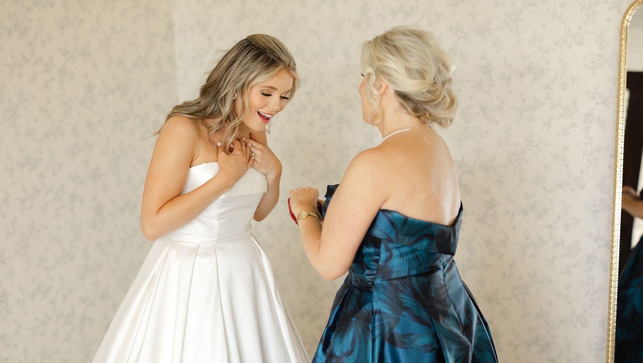 bride smiling down and mother and gift