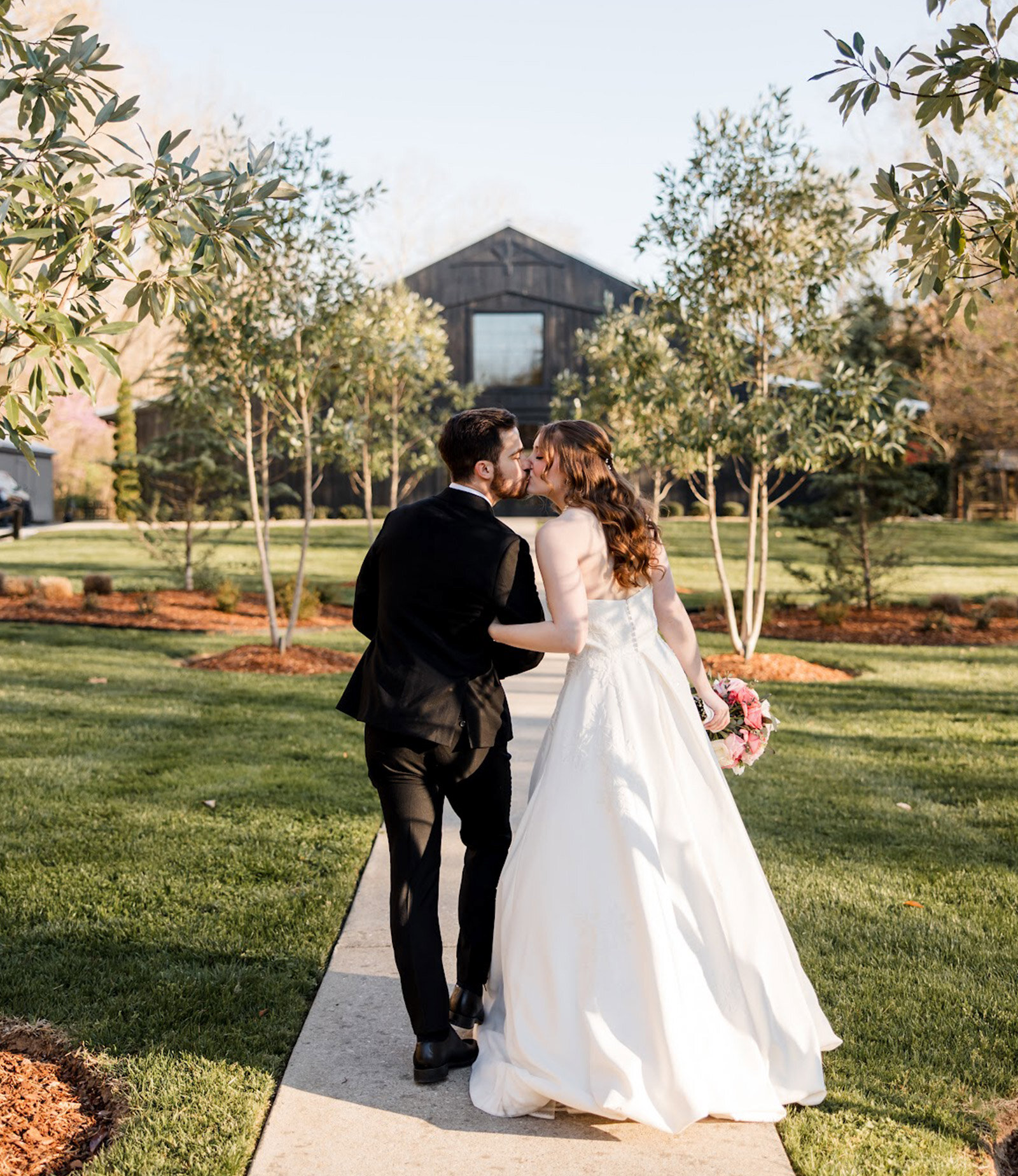 bride and groom kissing outside of barn wedding venue