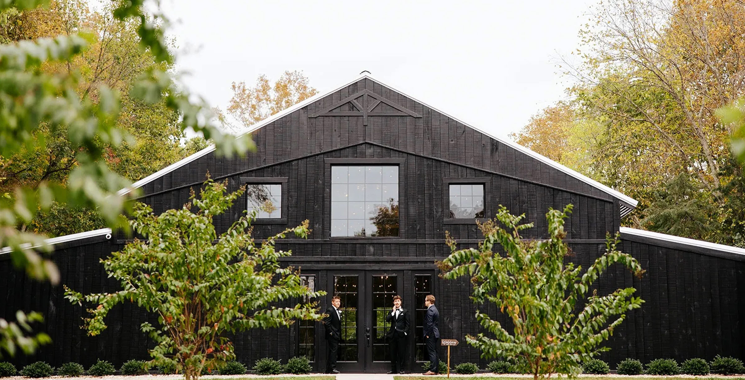 rustic modern black barn wedding venue surrounded by tall trees