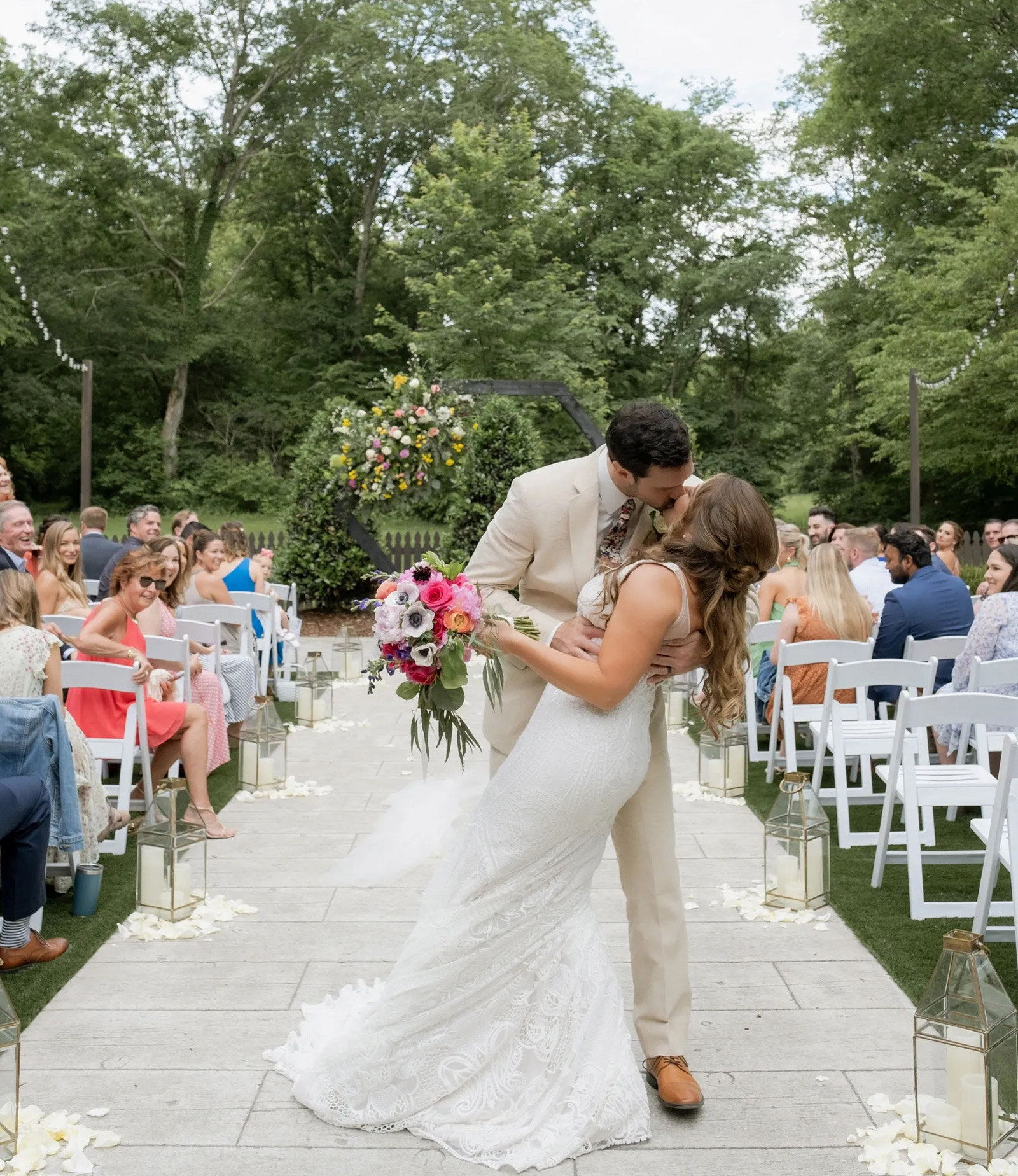 bride and groom kissing walking down the aisle after outdoor wedding ceremony in a garden