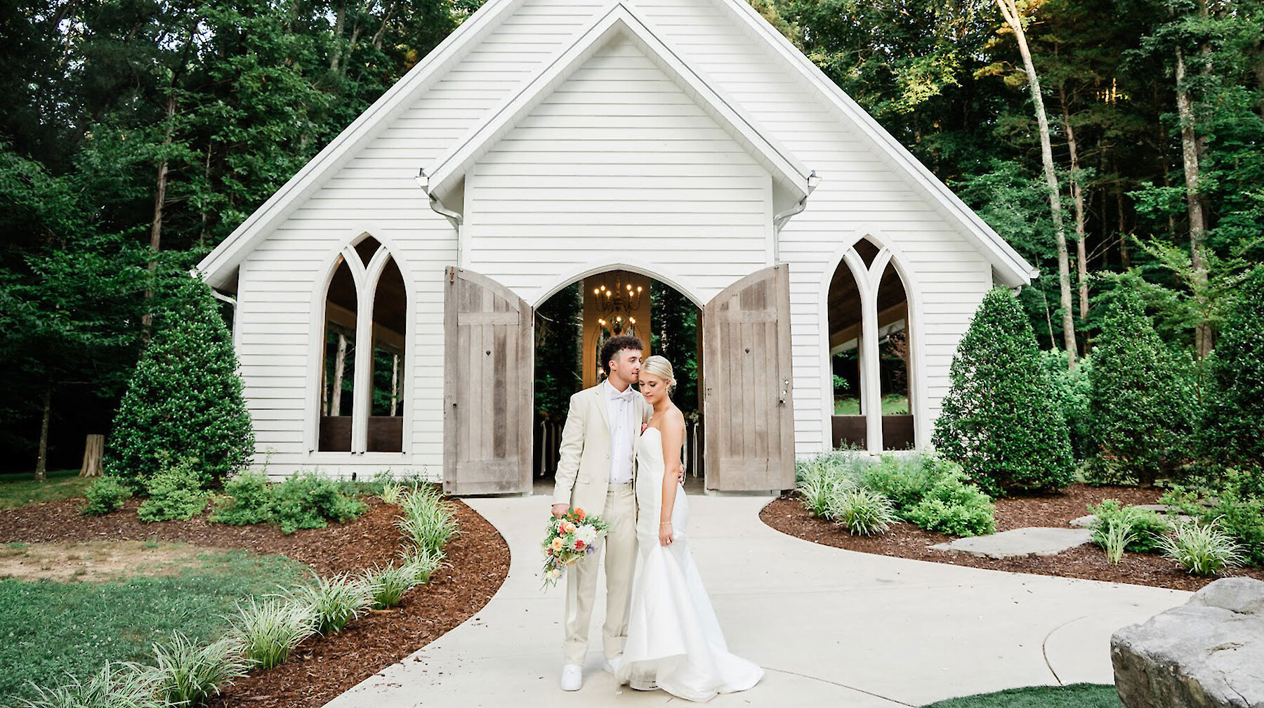 Bride and groom in front of white chapel