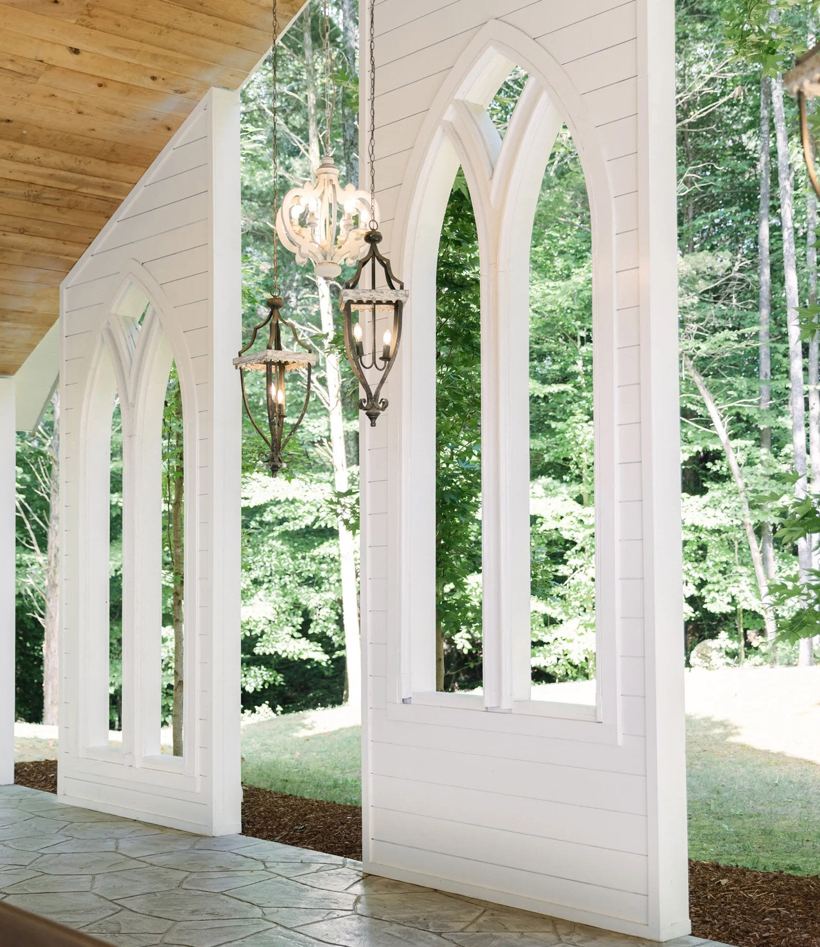 Open air white chapel with chandelier surrounded by tall trees