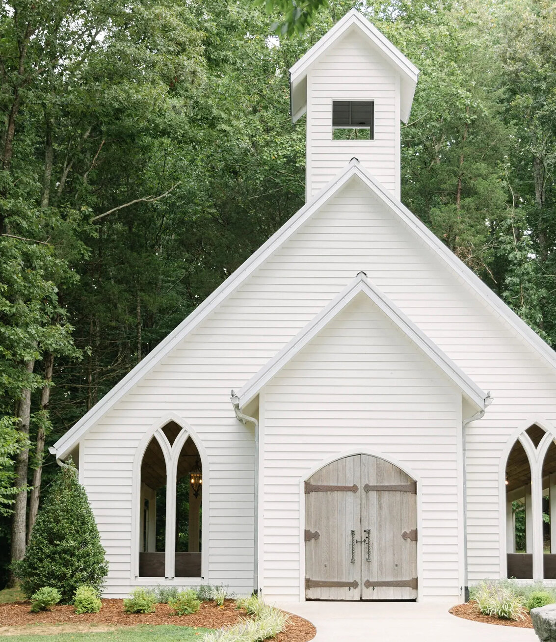 White chapel surrounded by tall trees