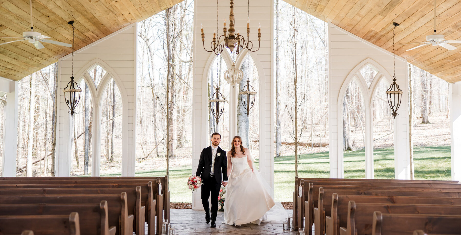 Bride and groom holding hands in open air chapel