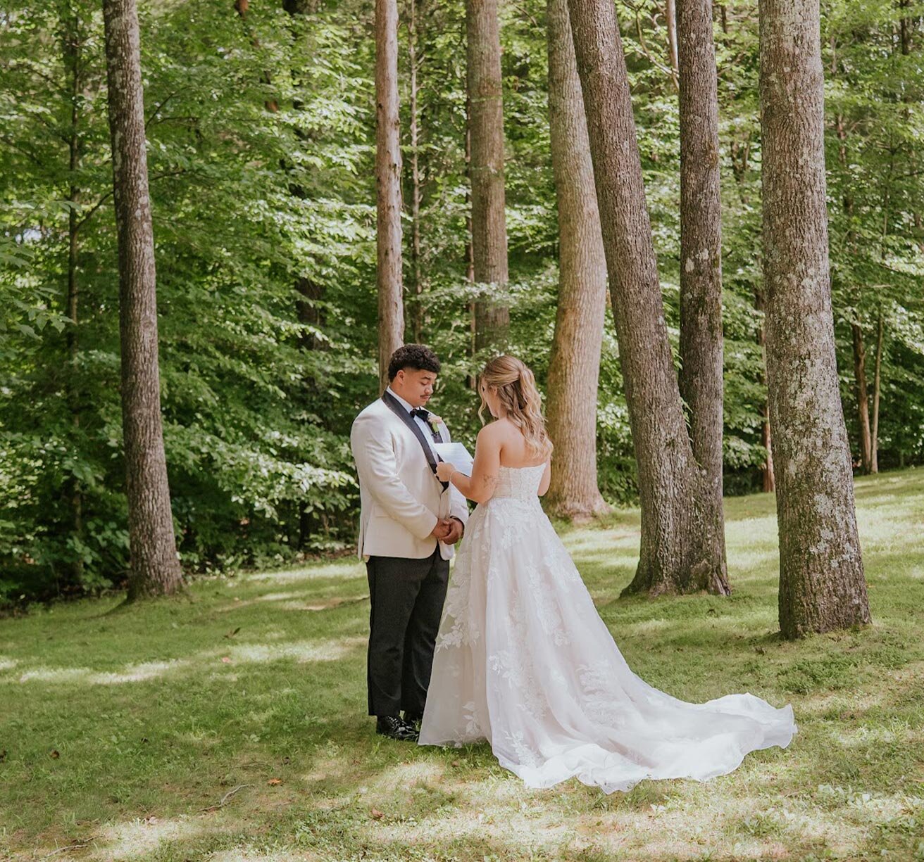 Bride and groom exchanigng vows outside under tall trees