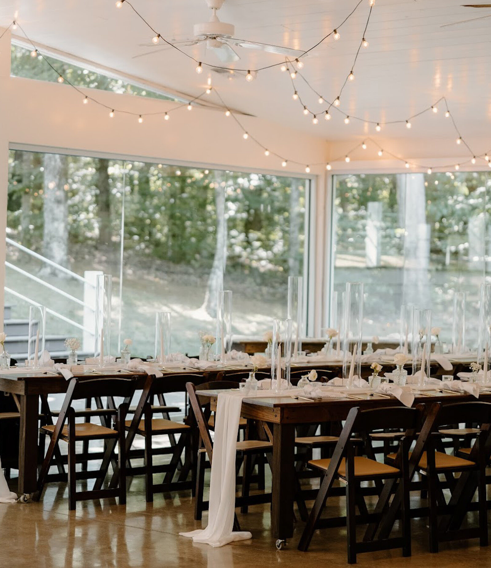 glass reception hall with string lights and table decor