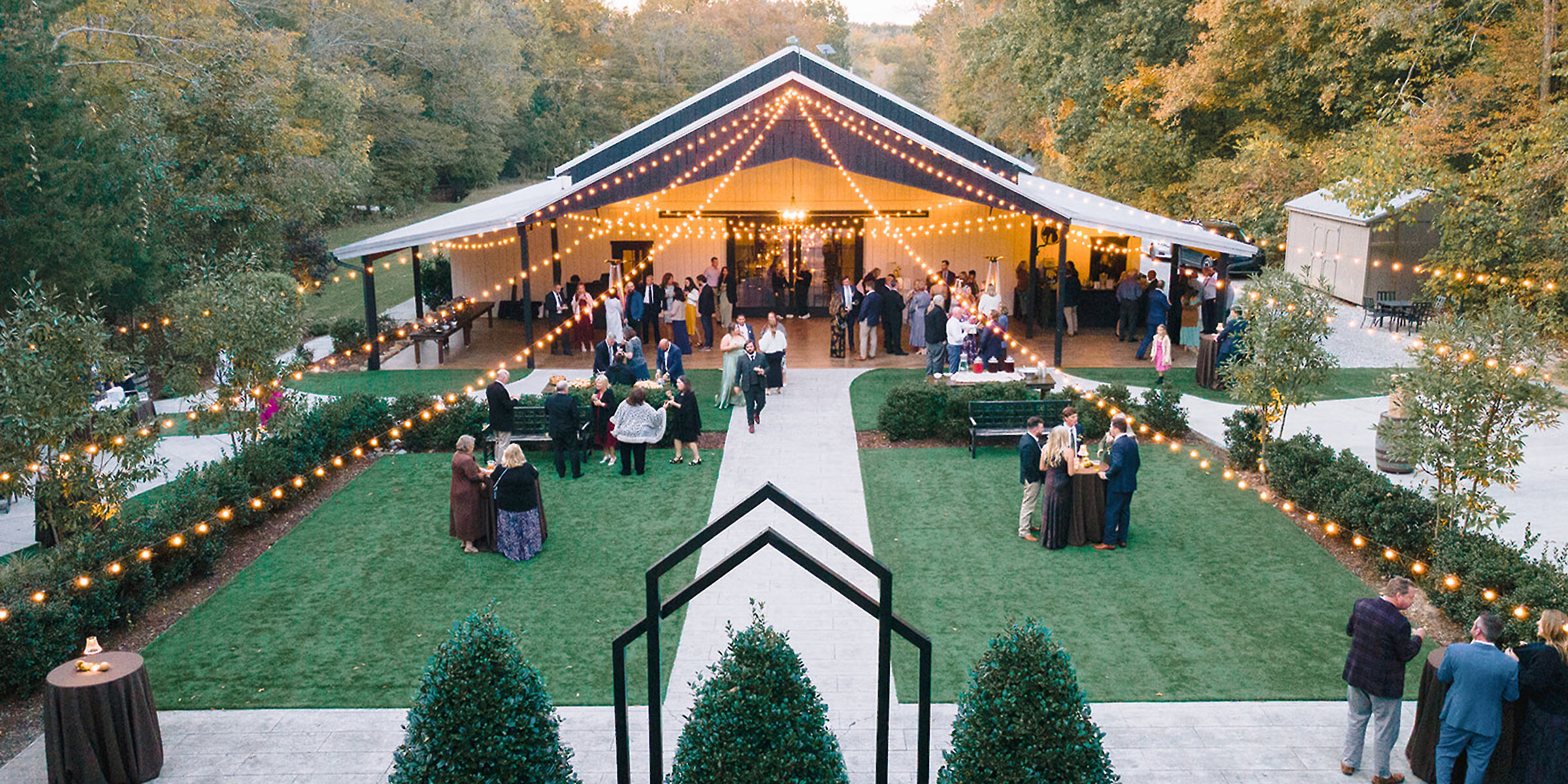 Outdoor wedding venue area with string lights surrounded by green trees and lush nature