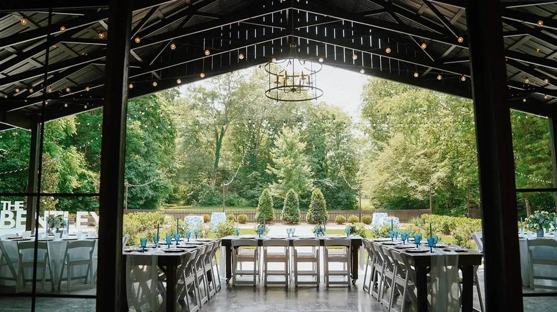 outdoor wedding reception under patio cover with string lights and views of tall trees in nature