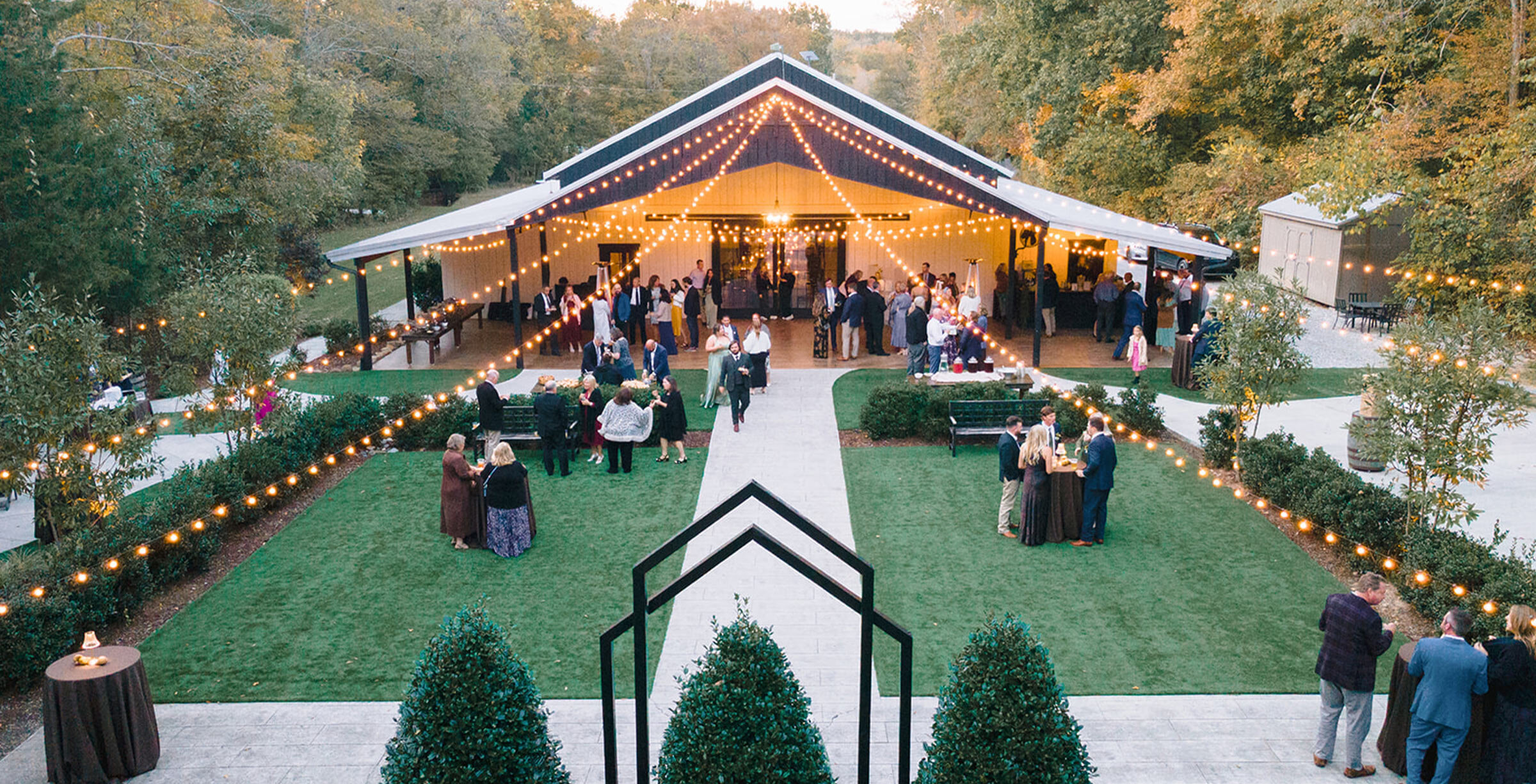 outdoor cocktail hour area with large patio and string lights usrrounded by nature and tall trees