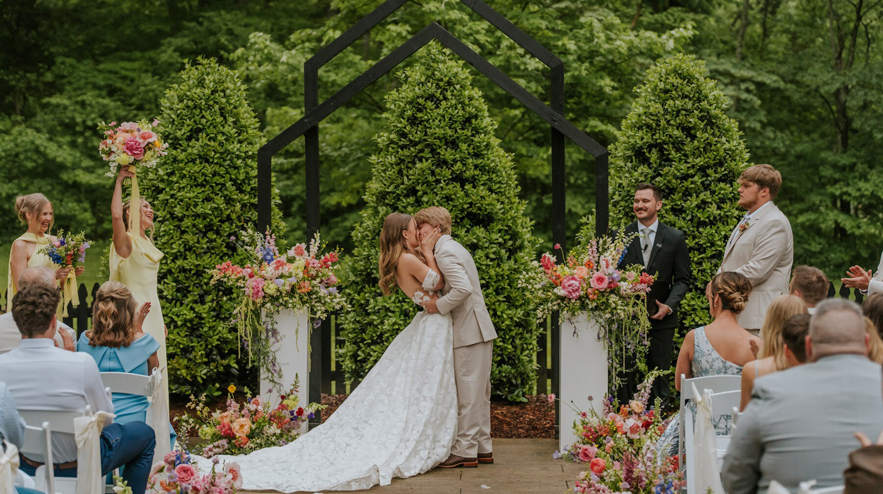 couple kissing at outdoor wedding ceremony in a gard