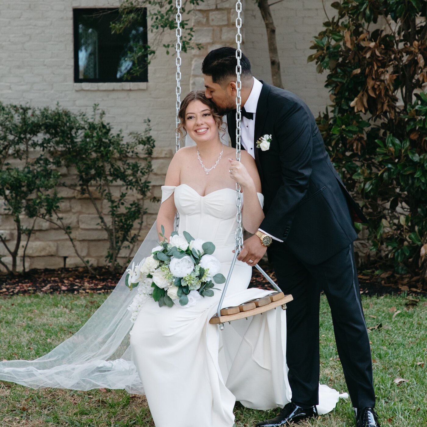 Close-up detail of the bride and groom clinking champagne flutes during a wedding toast. The photo highlights the bride's large engagement ring and the groom's tuxedo lapel with a white boutonnière.