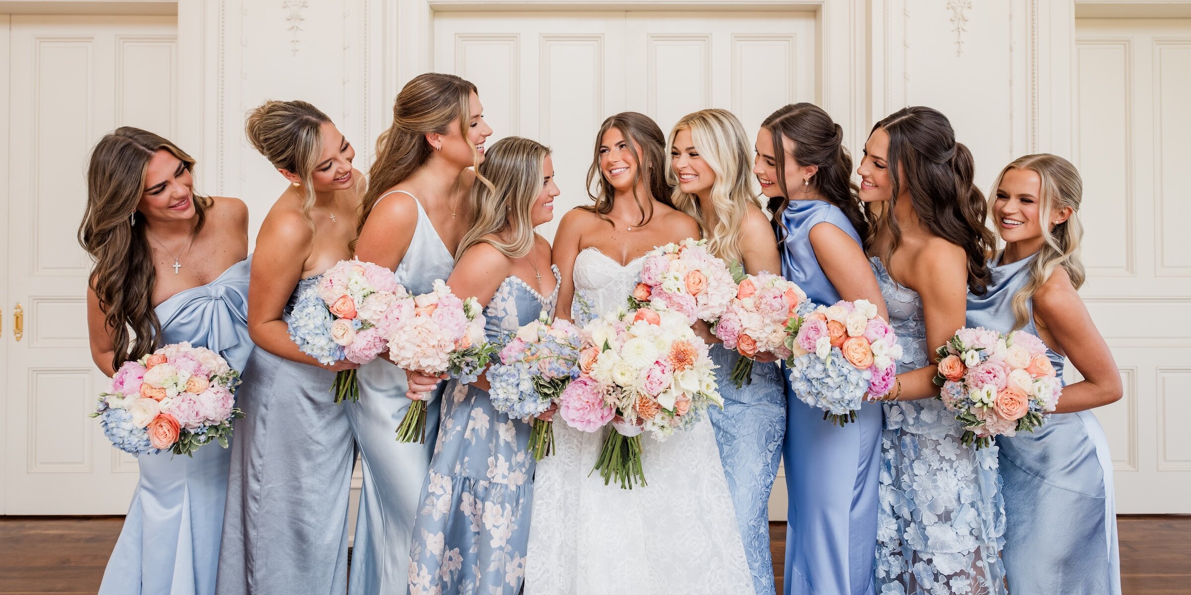 Bridal party in blue dresses with bride centred holding colourful bouquets