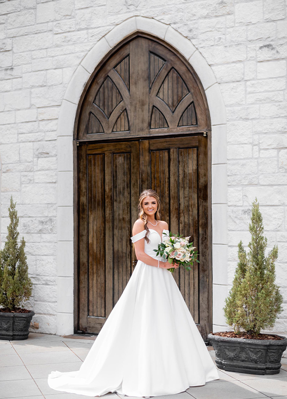 Bride holding bouquet in front of building with large wooden doors