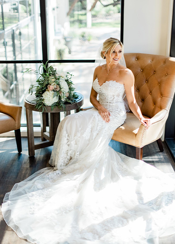Bride sitting on a chair in front of windows